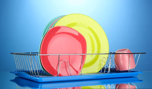 Color plates in rack on blue background — Stock Photo, Image