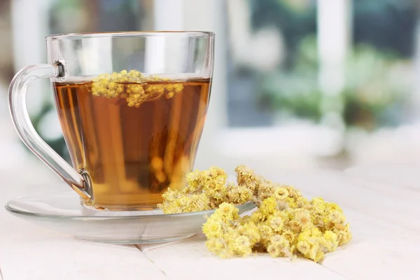 A cup of tea with immortelle on wooden table on window background — Stock Photo, Image