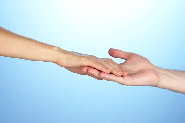 Women's hand goes to the man's hand on blue background Royalty Free Stock Photos