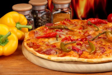 alev arka plan üzerinde ahşap tahta üzerinde sebze ile lezzetli biberli pizza