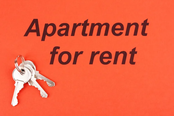 Anuncie aluguel apartmennt em papel vermelho em fundo de madeira close-up — Fotografia de Stock