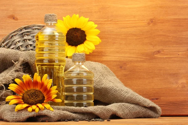 Olio in bottiglie, girasoli e semi, su fondo di legno — Foto Stock