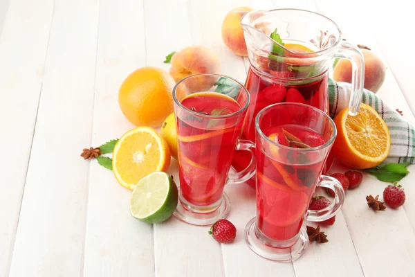 Sangria en pot et verres aux fruits, sur table en bois blanc — Photo