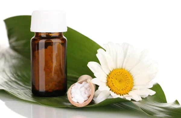 Homöopathische Tabletten und Blume auf grünem Blatt isoliert auf weißem Blatt — Stockfoto