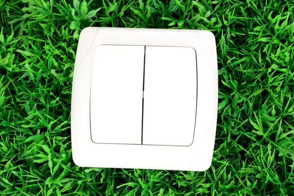 Modern light switch on green grass — Stock Photo, Image