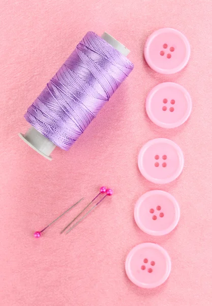 Boutons à coudre colorés avec fil sur tissu rose — Photo