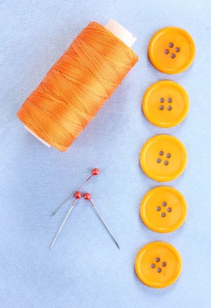 Colorful sewing buttons with thread on blue fabric — Stock Photo, Image