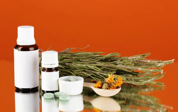 Flaschen mit Medikamenten und Kräutern auf orangefarbenem Hintergrund. Konzept der Homöopathie — Stockfoto