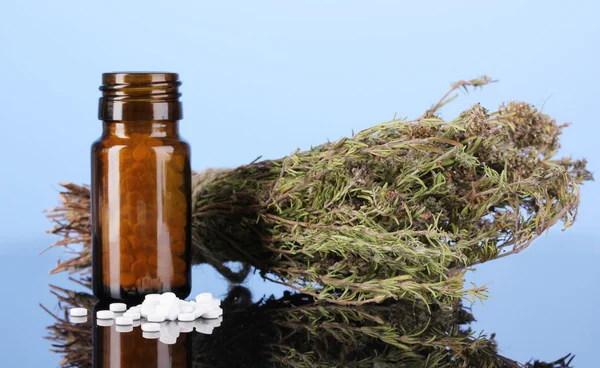 Fles met pillen en kruiden op blauwe achtergrond. concept van de homeopathie — Stockfoto