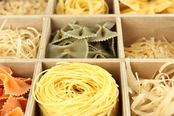 Nine types of pasta in wooden box sections close-up — Stock Photo, Image