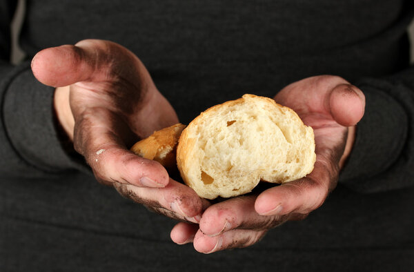 Homeless man holding a white bread, close-up