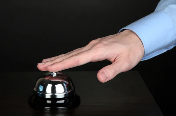 Hand ringing in service bell on wooden table on black background — Stock Photo, Image