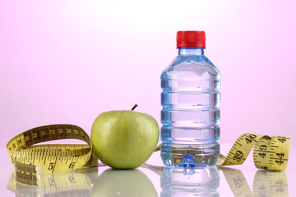 Flasche Wasser, Apfel und Maßband auf violettem Hintergrund — Stockfoto