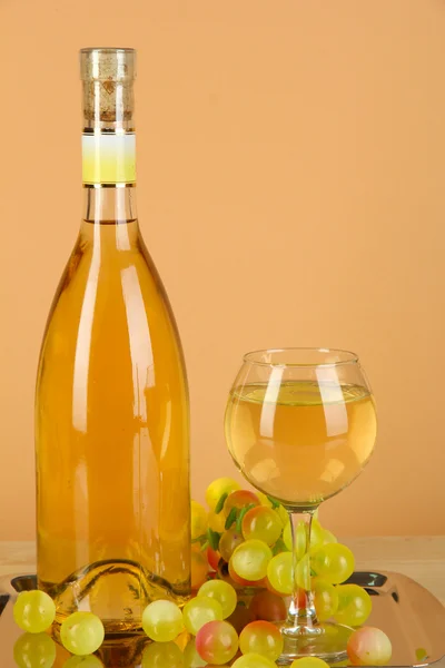 ベージュ色の背景に金属製の盆にボトルとグラス白ワイン — ストック写真