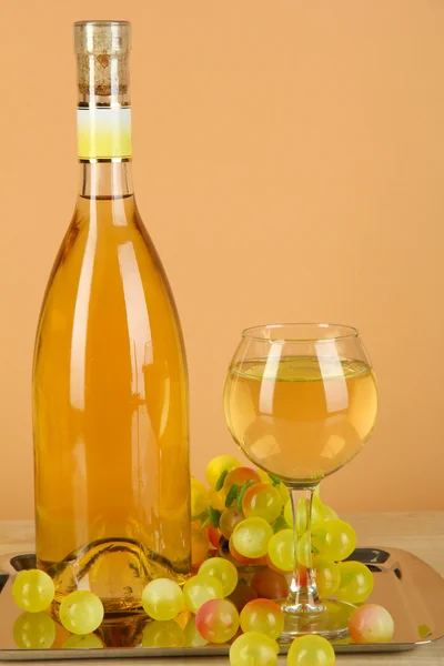 Witte wijn in glas met fles op salver op beige achtergrond — Stockfoto