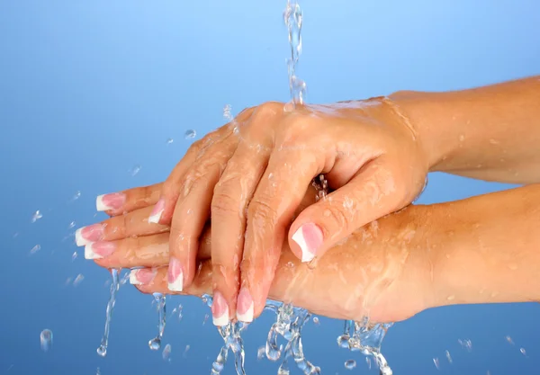 Laver les mains de la femme sur fond bleu gros plan — Photo