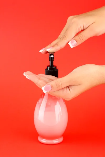 Woman squeezing lotion on her hand, on red background close-up — Stock Photo, Image