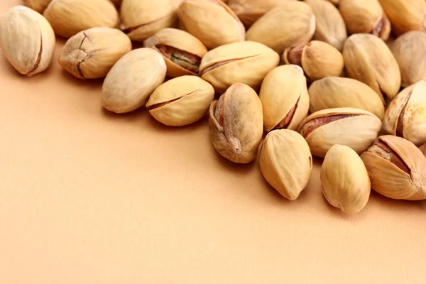 Tasty pistachio nuts, on beige background — Stock Photo, Image