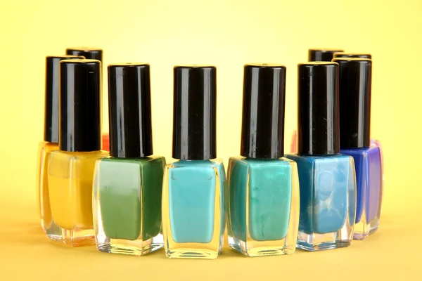 Group of bright nail polishes, on yellow background — Stock Photo, Image