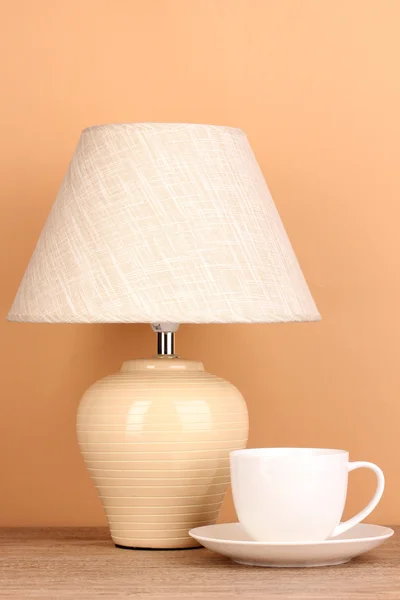 Table lamp and cup on beige background — Stock Photo, Image