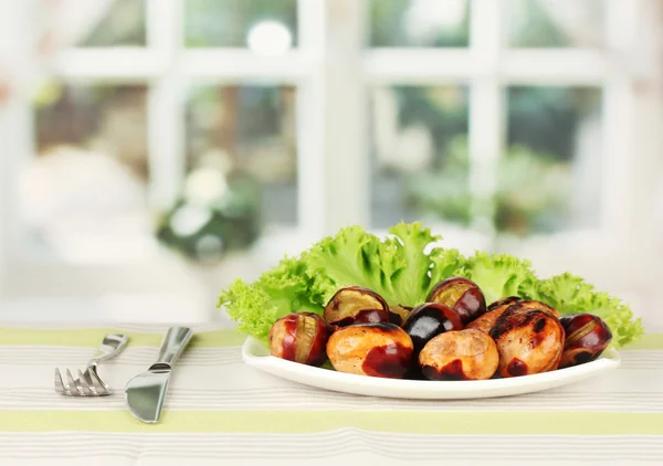 Roasted chestnuts with lettuce in the plate on the tablecloth close-up — Stock Photo, Image