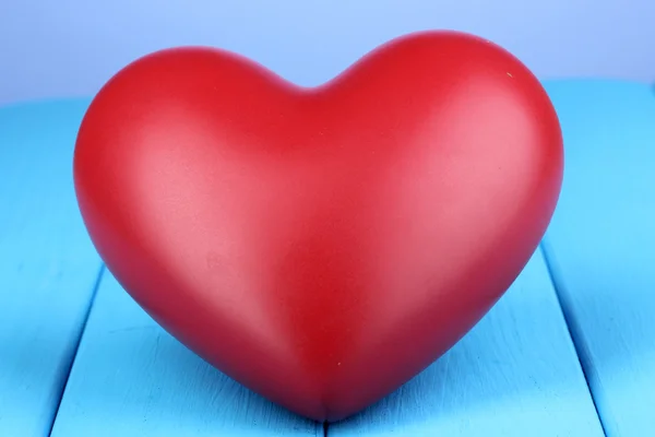 Corazón rojo decorativo sobre mesa de madera azul sobre fondo azul — Foto de Stock