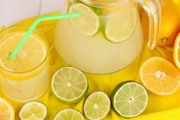Limonada cítrica en vidrio y jarra de cítricos alrededor en tela amarilla en w —  Fotos de Stock