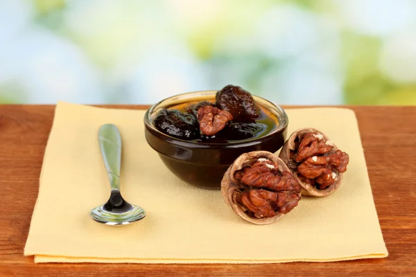Jam walnuts in a bowl on a table on a green background — Stock Photo, Image