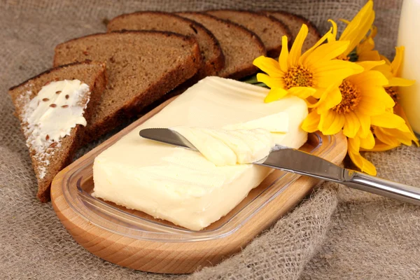 Boter op houten houder omringd door brood en bloemen op plundering CHTERGRO — Stockfoto