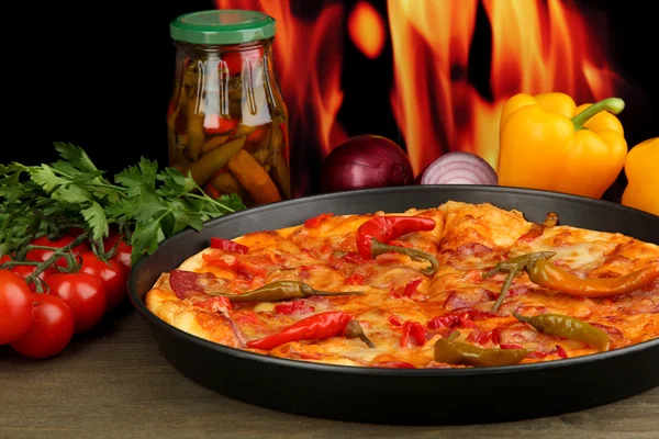 Pizza pepperoni savoureuse dans une casserole avec des légumes sur fond de flamme — Photo