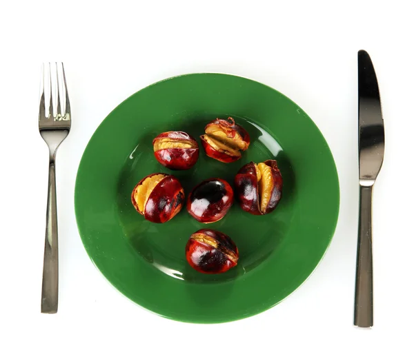 Roasted chestnuts in the green plate with fork and knife isolated on white Royalty Free Stock Photos