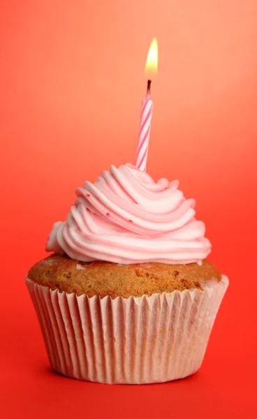 Tasty birthday cupcake with candle, on red background — Stock Photo, Image