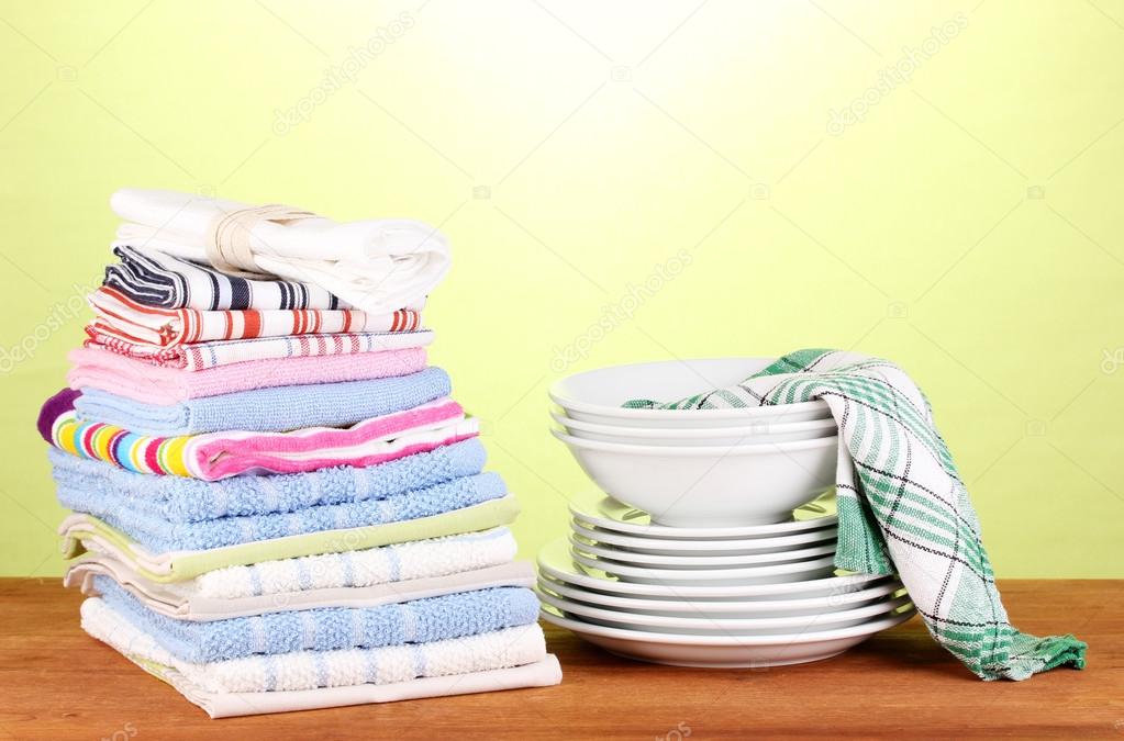 Kitchen towels with dishes on green background close-up