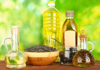 Olive and sunflower oil in the bottles and small decanters on green backgro clipart