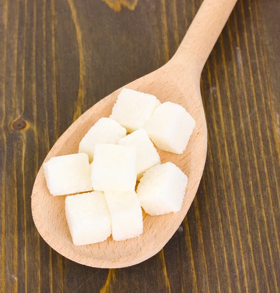 Açúcar branco na colher no fundo de madeira — Fotografia de Stock