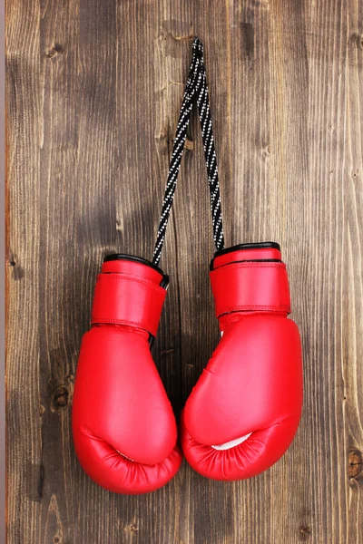 Rote Boxhandschuhe hängen auf Holzgrund — Stockfoto