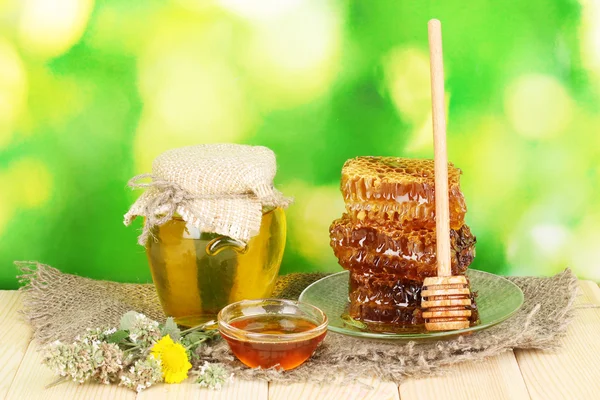 Jar of honey and honeycomb on wooden table on nature background — Stock Photo, Image