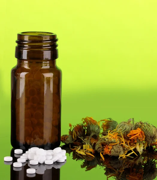 Frasco con pastillas y hierbas sobre fondo verde. concepto de homeopatía — Foto de Stock