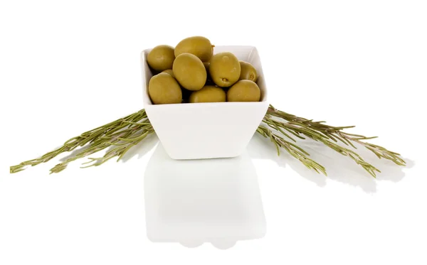 Gröna oliver i vit skål med rosmarin isolerad på vit — Stockfoto
