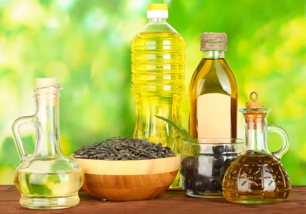 Olive and sunflower oil in the bottles and small decanters on green backgro — Stock Photo, Image