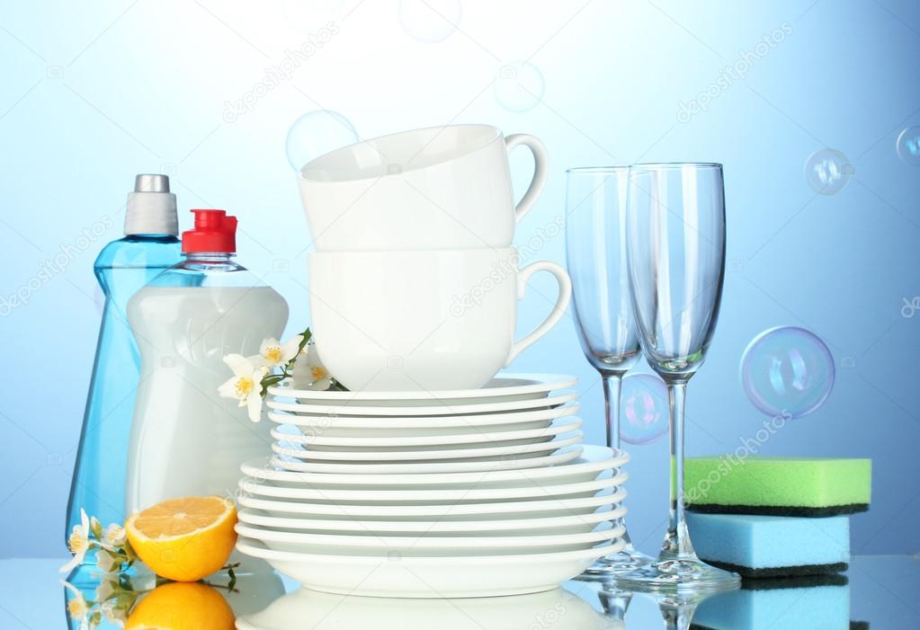 Empty clean plates, glasses and cups with dishwashing liquid, sponges and l