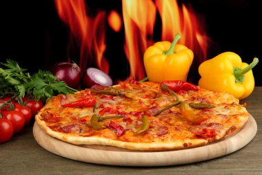 alev arka plan üzerinde ahşap tahta üzerinde sebze ile lezzetli biberli pizza