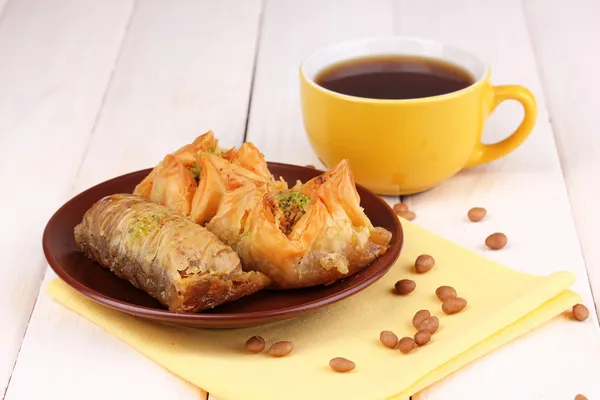 Zoete baklava op plaat met thee op houten achtergrond — Stockfoto