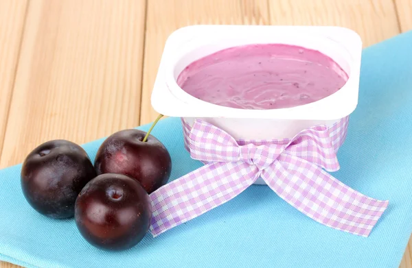 Yoghurt met bosbessen en pruimen op houten tafel — Stockfoto