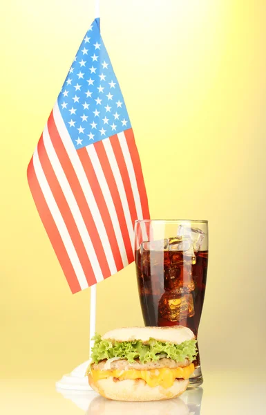 Sanduíche saboroso e cola com bandeira americana, no fundo amarelo — Fotografia de Stock