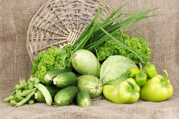 Свежие зеленые овощи на фоне мешковины — стоковое фото