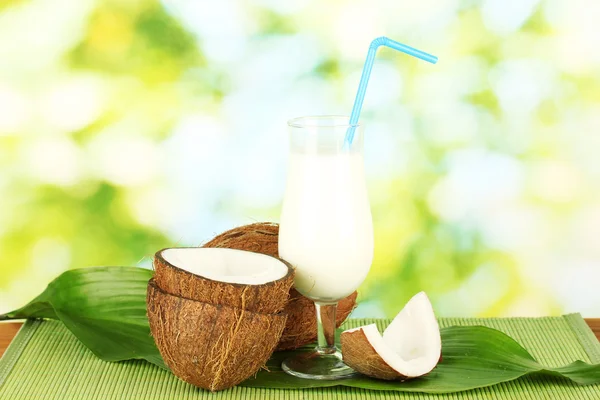 Vidro de leite de coco e cocos em fundo verde close-up — Fotografia de Stock