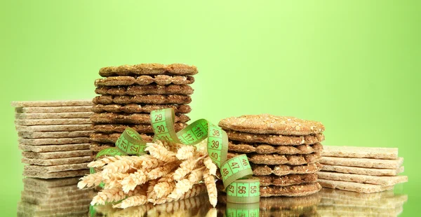 Leckeres Knäckebrot, Ohren und Maßband, auf grünem Hintergrund — Stockfoto