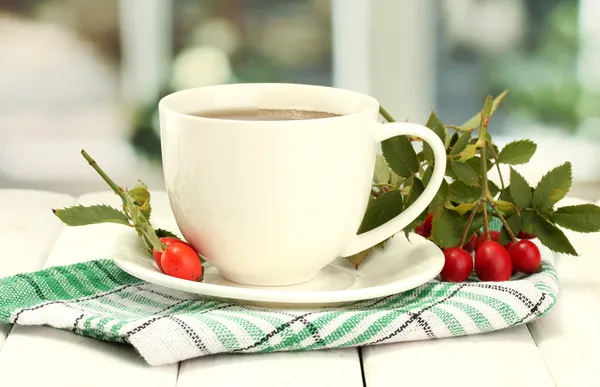 Kopje thee met hip rozen, op houten tafel — Stockfoto