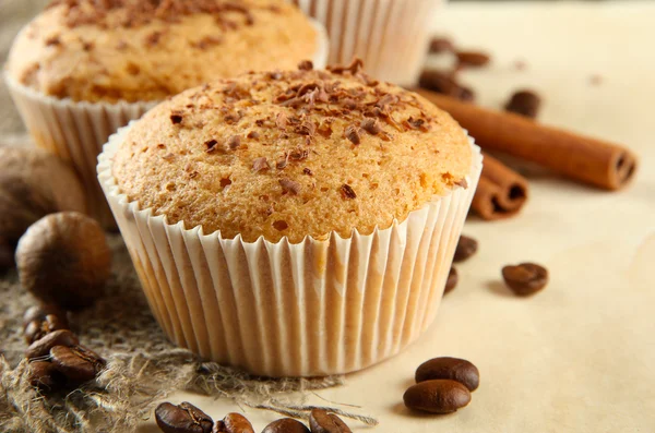 Tasty muffin cakes with chocolate, spices and coffee seeds, on beige backgr — Zdjęcie stockowe